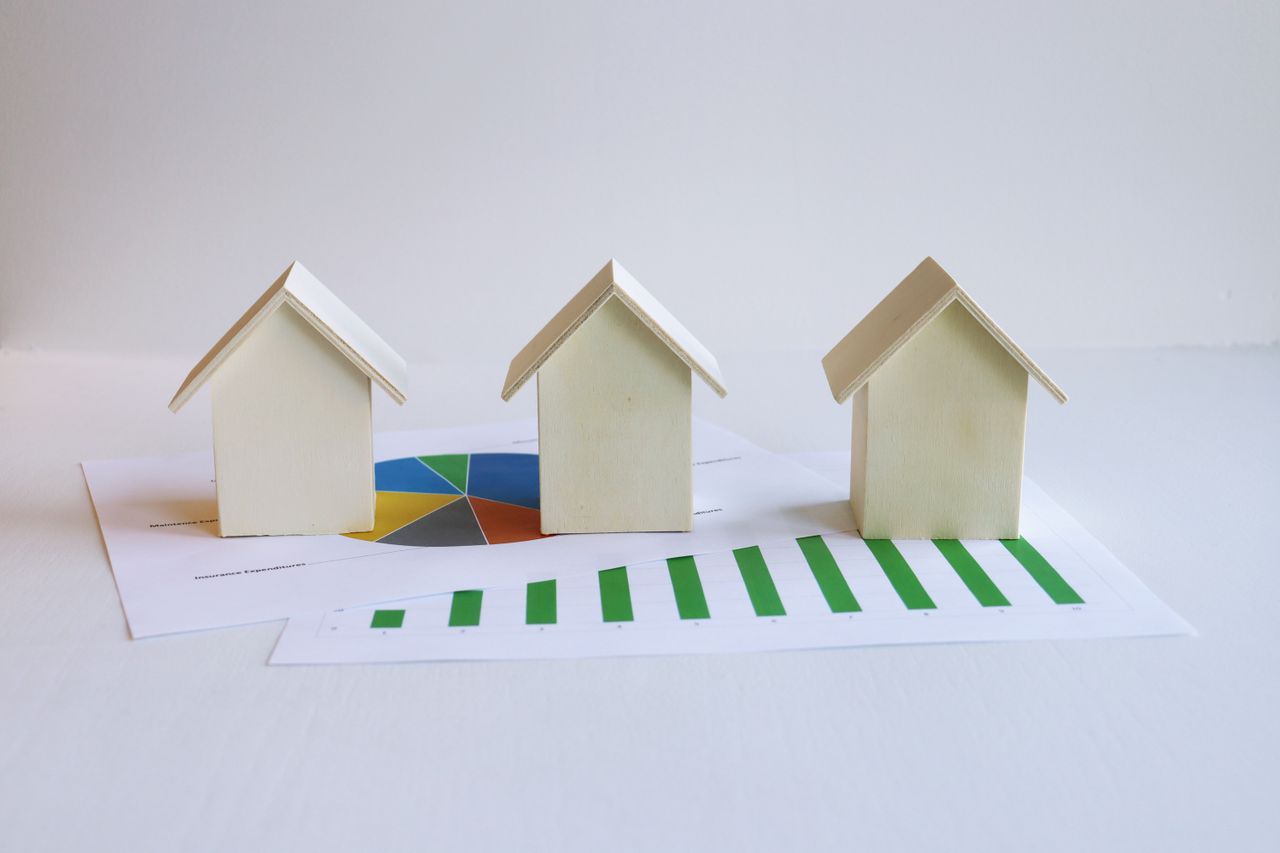 about-02 Wooden model houses on graphs depict real estate market analysis and trends.